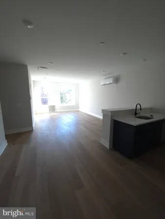a white kitchen with stainless steel appliances a sink a stove a microwave a refrigerator a white cabinets and wooden floor