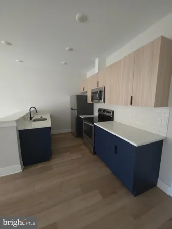 a kitchen with stainless steel appliances a sink a stove top oven a counter space and cabinets