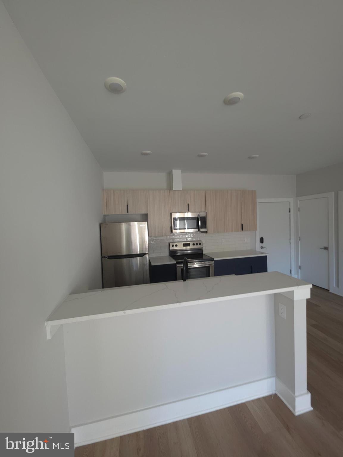3503 Midvale Avenue, Unit 506 Philadelphia, PA 19129 - Photo 26 of 40 a white kitchen with stainless steel appliances a sink a stove a microwave a refrigerator a white cabinets and wooden floor