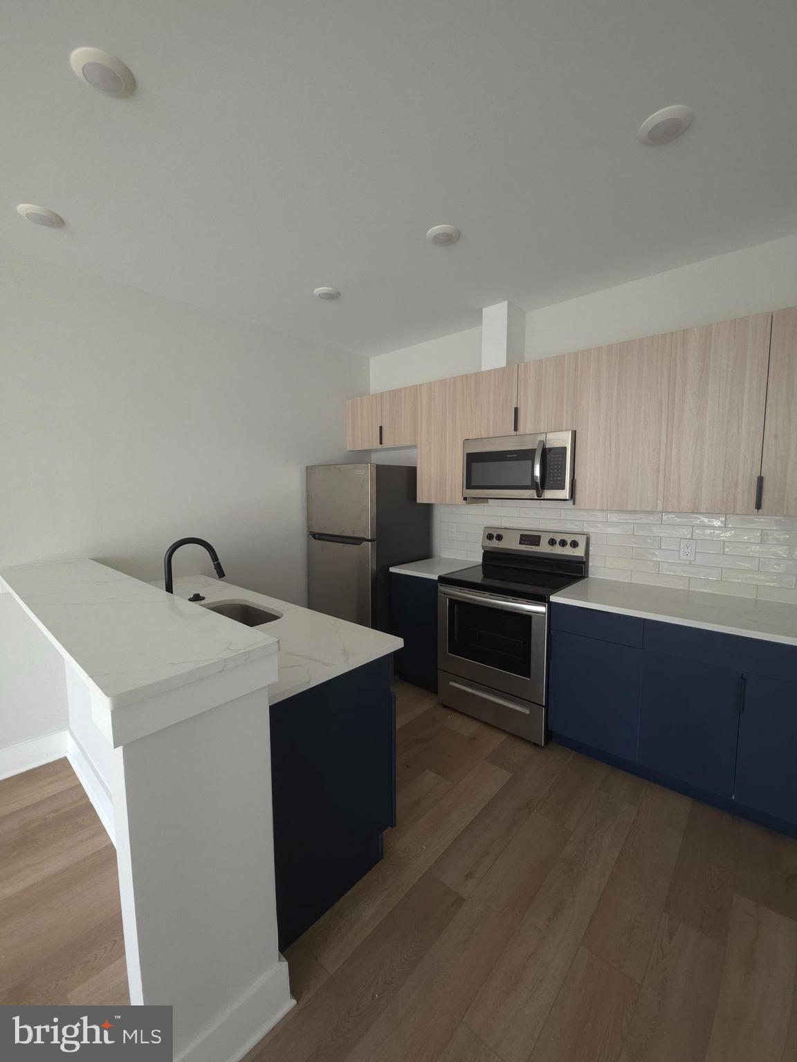 3503 Midvale Avenue, Unit 506 Philadelphia, PA 19129 - Photo 27 of 40 a kitchen with stainless steel appliances a sink a stove top oven a counter space and cabinets