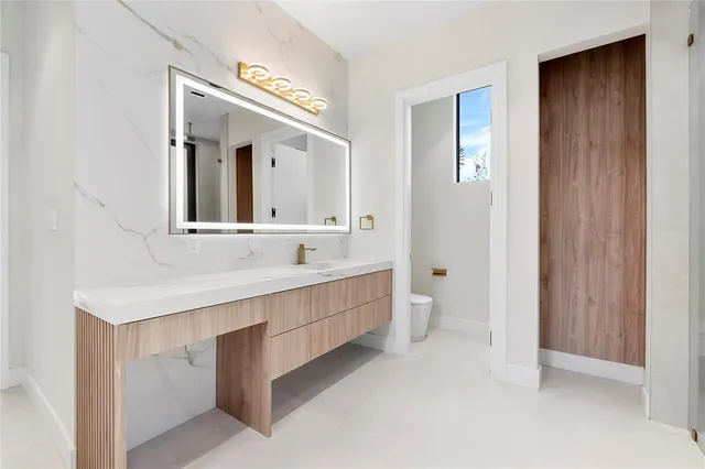 a bathroom with a bathtub shower sink vanity mirror and toilet