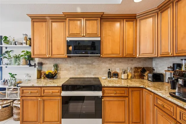 a kitchen with stainless steel appliances granite countertop wooden cabinets a stove a sink and a window