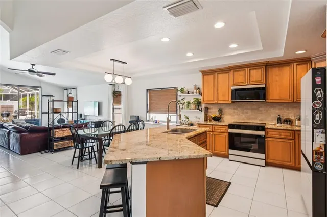 a kitchen with granite countertop a stove top oven a sink dishwasher a dining table and chairs with wooden floor