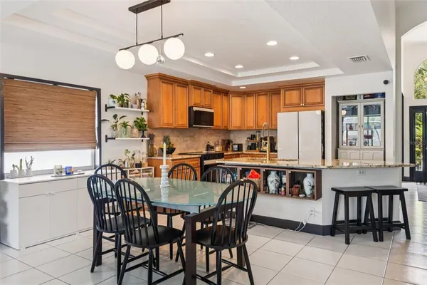 a kitchen with stainless steel appliances granite countertop a stove a refrigerator a kitchen island a table and chairs