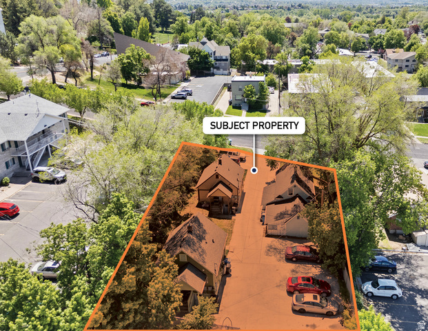 661 East 600 North Logan, UT 84321 - Photo 3 of 15 Aerial overview showcasing multiple structures within the property boundary, featuring gabled rooflines, light-colored siding, and mature surrounding trees