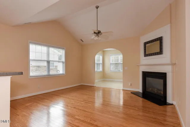 an empty room with windows fireplace and wooden floor