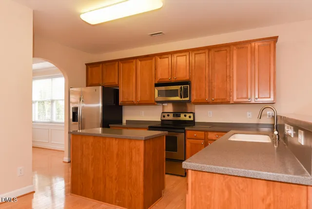 a kitchen with stainless steel appliances granite countertop a sink stove refrigerator and microwave