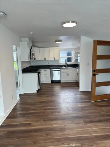 a kitchen with stainless steel appliances granite countertop a sink cabinets and wooden floor