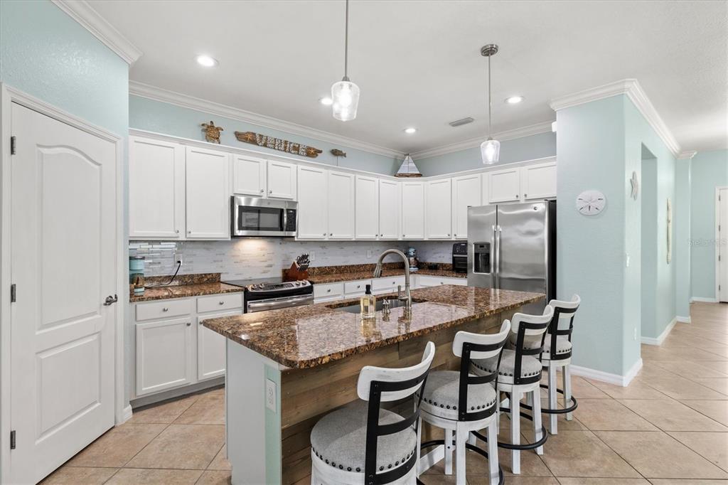 12675 Richezza Drive Venice, FL 34293 - Photo 9 of 60 a kitchen with stainless steel appliances granite countertop a stove a sink a microwave a refrigerator and white cabinets with wooden floor