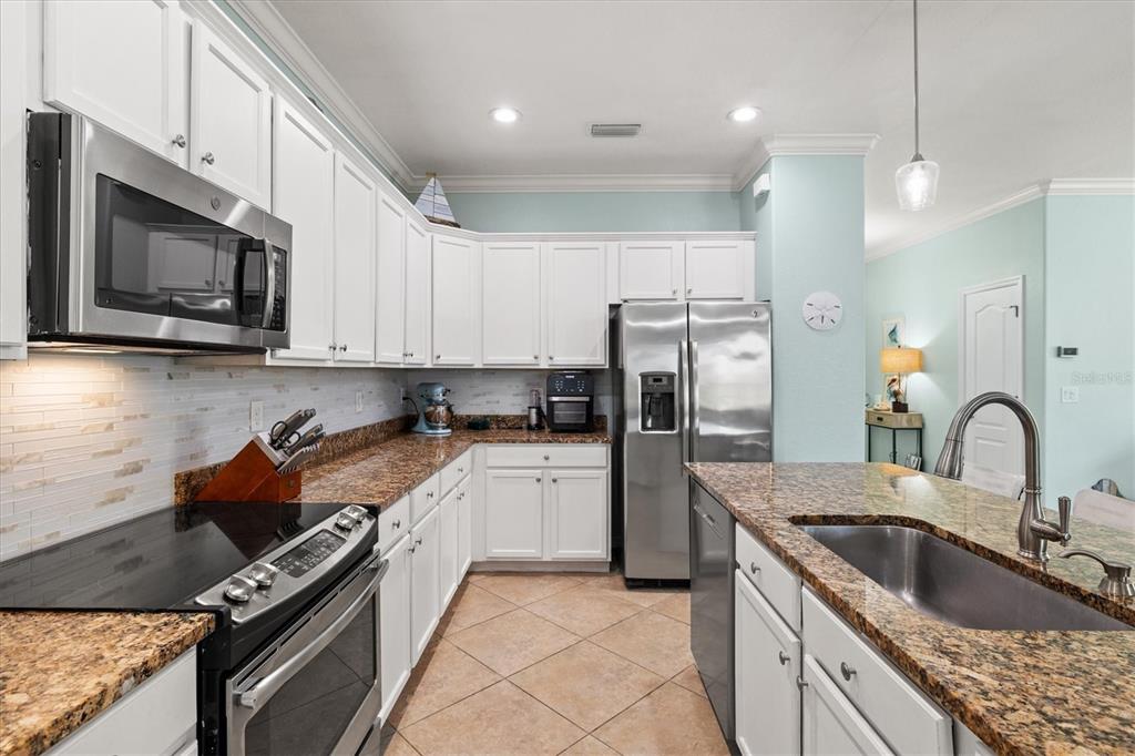 12675 Richezza Drive Venice, FL 34293 - Photo 10 of 60 a kitchen with granite countertop a sink stainless steel appliances and cabinets
