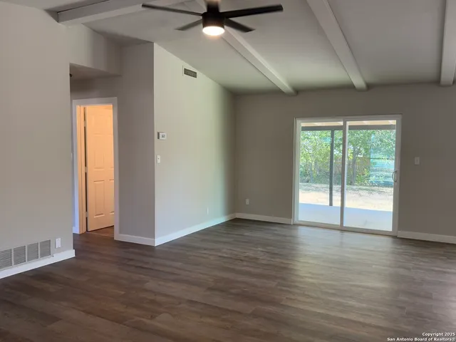 a view of an empty room with wooden floor and a window