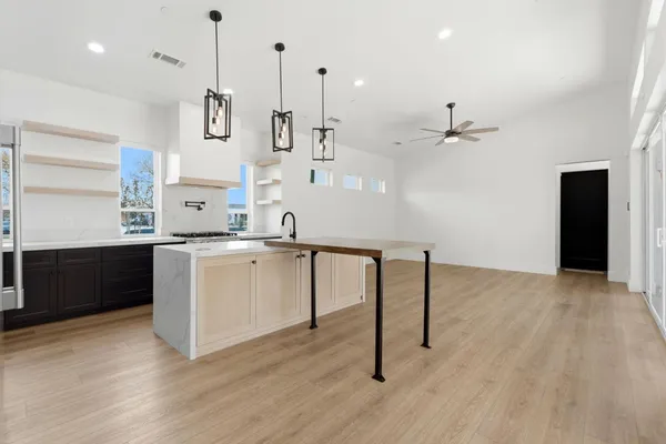 an empty room with wooden floor cabinet and windows