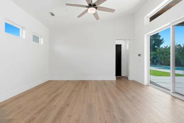 an empty room with wooden floor chandelier and windows