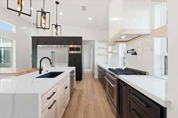 a view of an empty room with wooden floor and kitchen