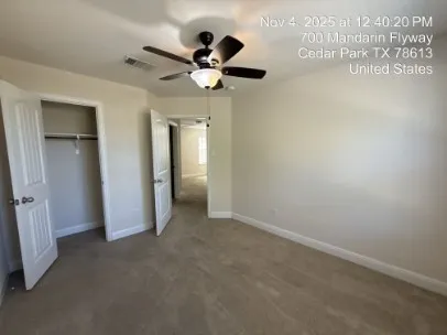 an empty room with ceiling fan and windows