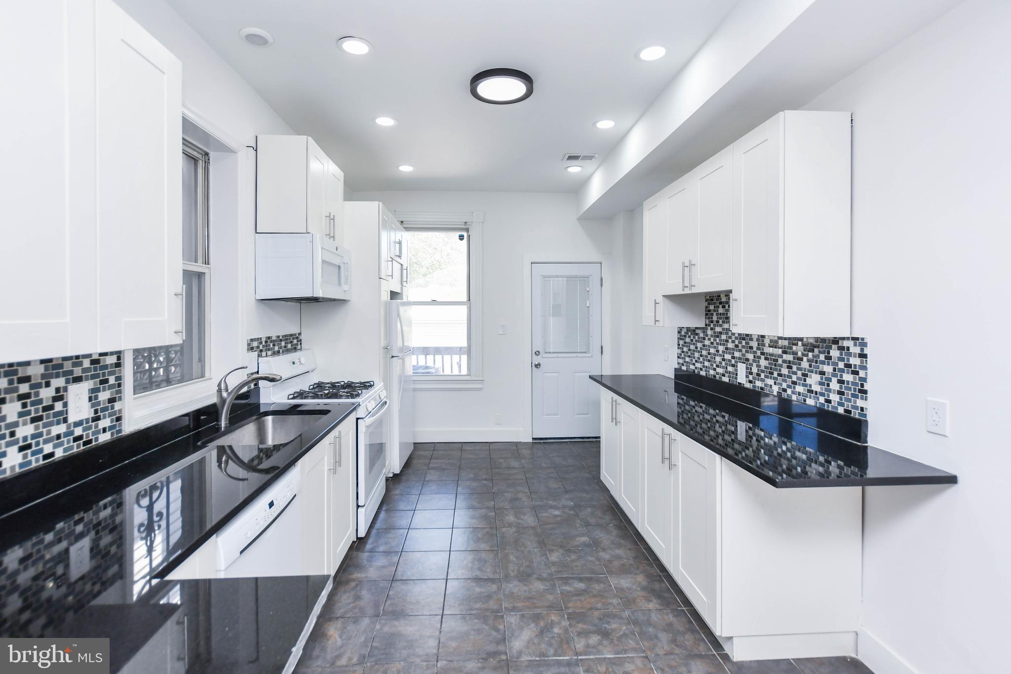 104 R Street Northeast, Unit A Washington, DC 20002 - Photo 12 of 43 a large kitchen with stainless steel appliances kitchen island granite countertop a stove a sink and a refrigerator