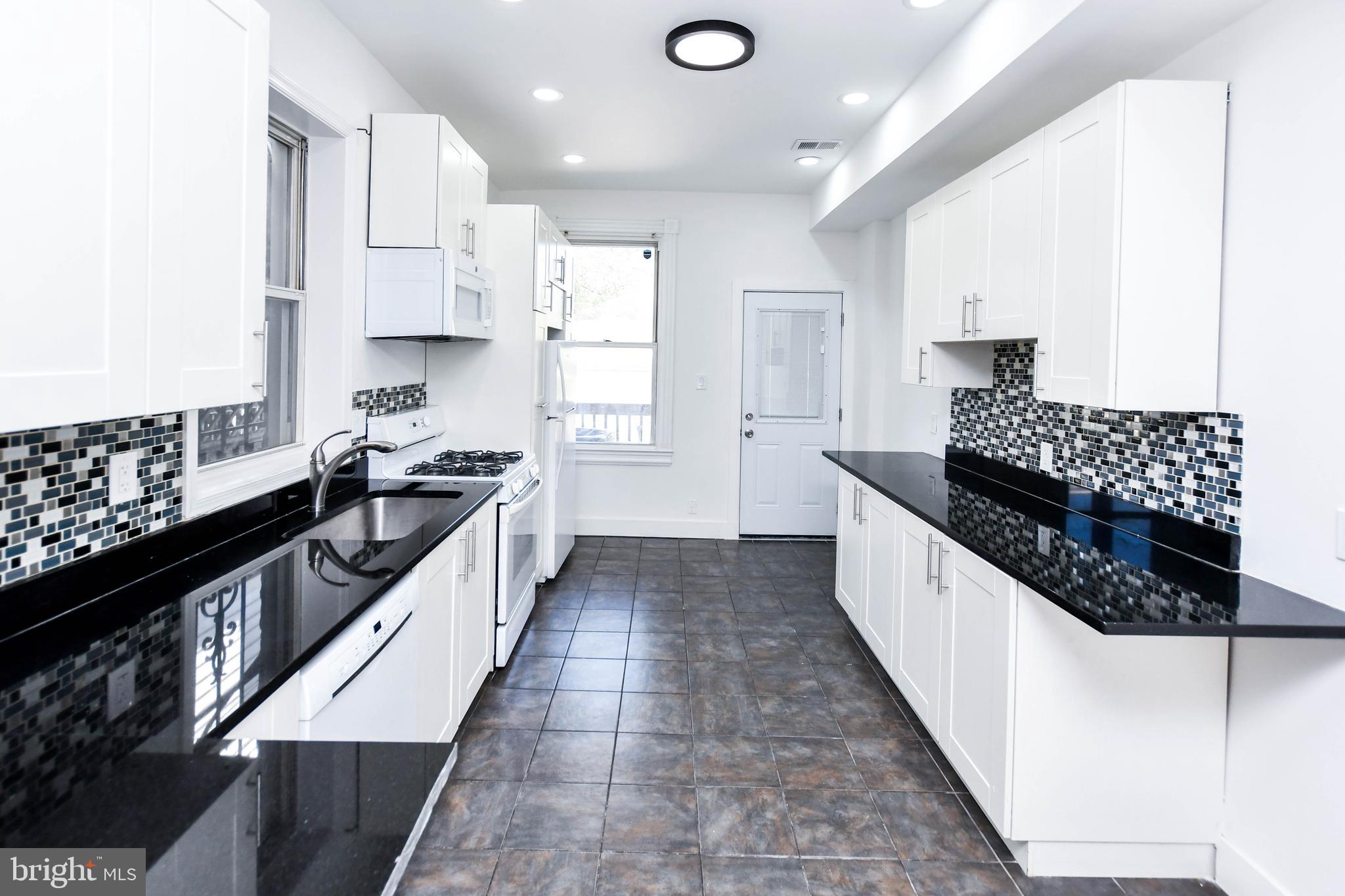 104 R Street Northeast, Unit A Washington, DC 20002 - Photo 13 of 43 a kitchen with stainless steel appliances kitchen island granite countertop a sink and cabinets