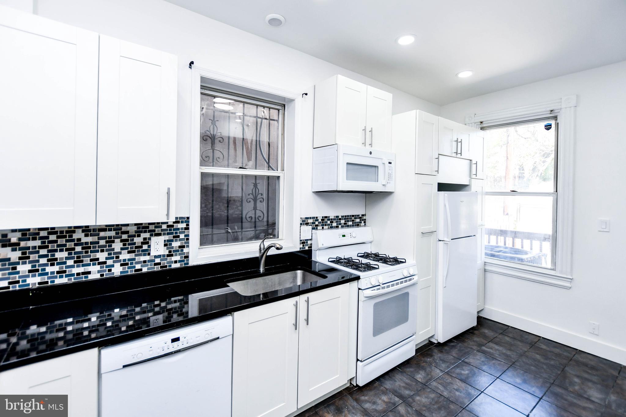 104 R Street Northeast, Unit A Washington, DC 20002 - Photo 15 of 43 a kitchen with stainless steel appliances a sink a stove and white cabinets