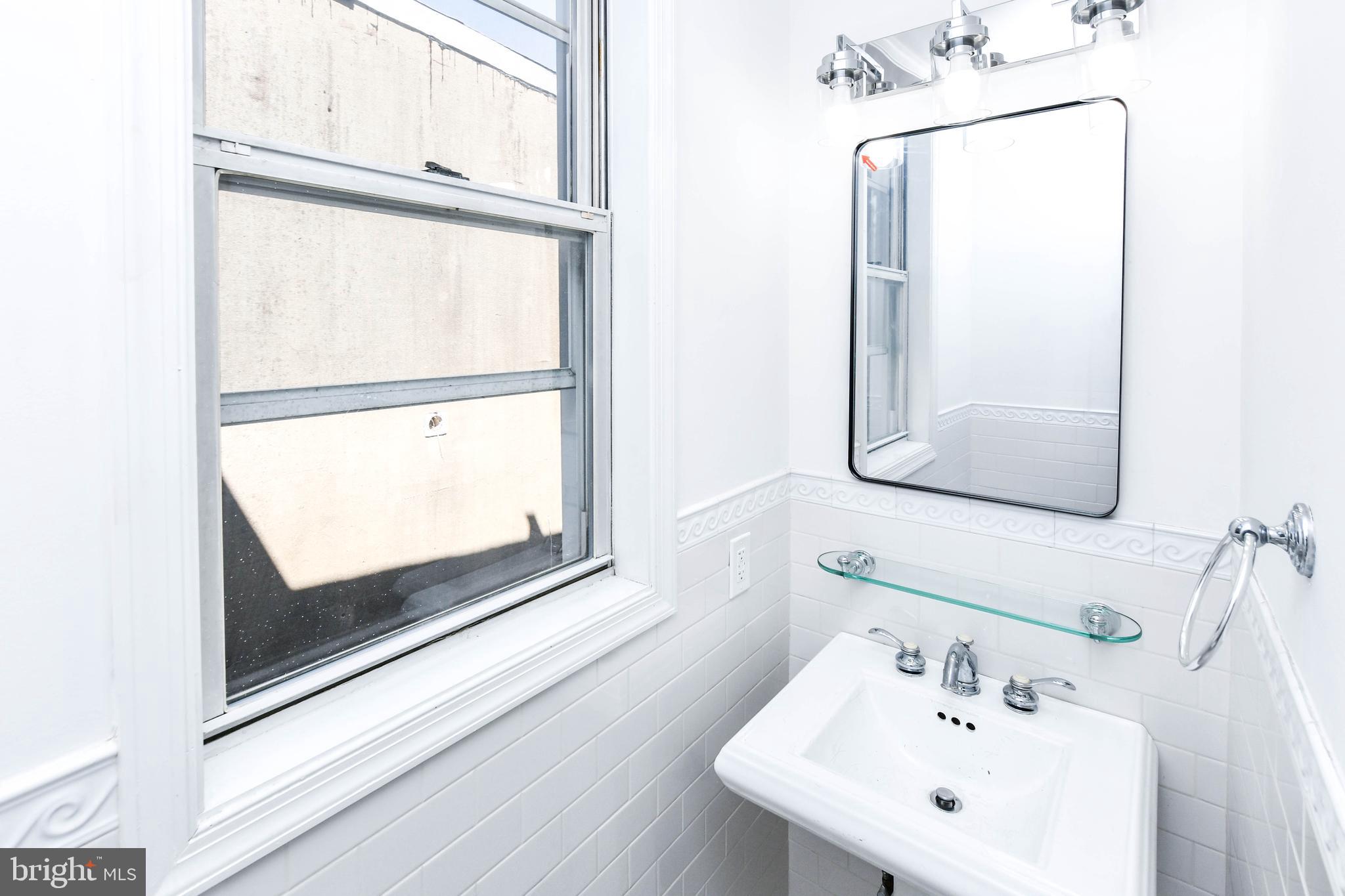 104 R Street Northeast, Unit A Washington, DC 20002 - Photo 26 of 43 a bathroom with a sink a mirror and a window