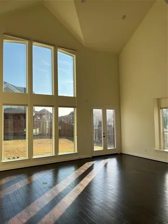 a view of an empty room with a window and wooden floor