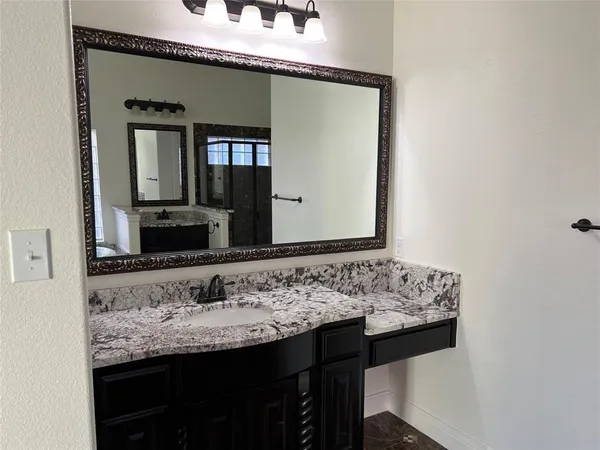 a bathroom with a granite countertop sink and a mirror