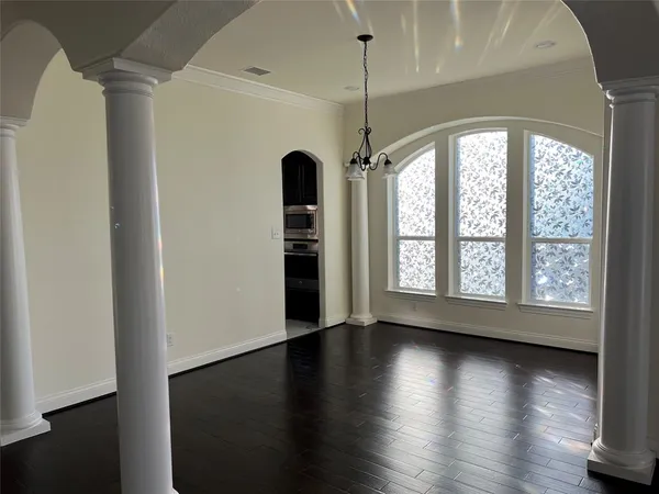 an empty room with wooden floor chandelier and windows