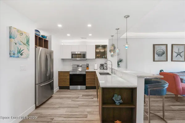 a large kitchen with stainless steel appliances granite countertop a refrigerator a oven and a sink with cabinets