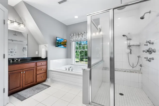 a bathroom with a tub sink shower and mirror
