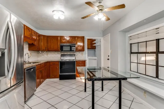 a kitchen with stainless steel appliances granite countertop a refrigerator a stove a sink a dining table and chairs with wooden floor