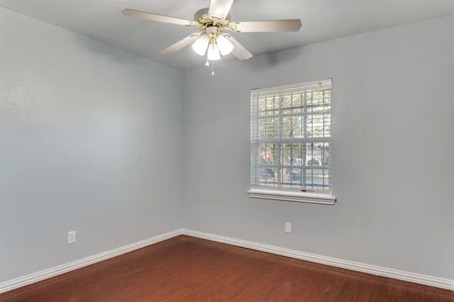 an empty room with a window and a fan