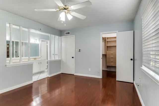a view of an empty room with window and wooden floor