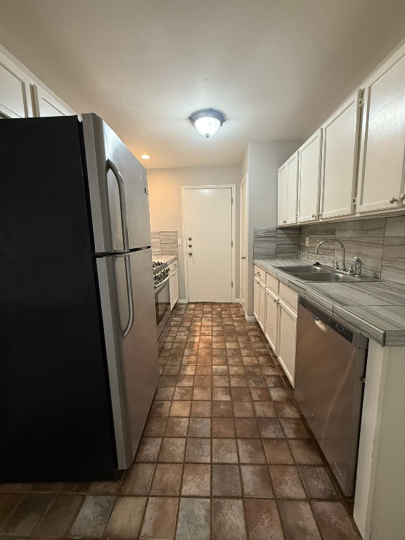 1904 Alex Avenue, Unit A Austin, TX 78728 - Photo 6 of 15 Kitchen featuring stainless steel appliances, white cabinets, backsplash, and tile counters