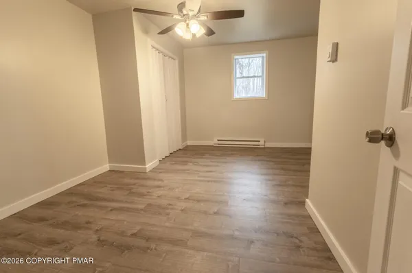 a view of an empty room with wooden floor and a window