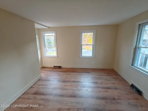 an empty room with wooden floor and windows