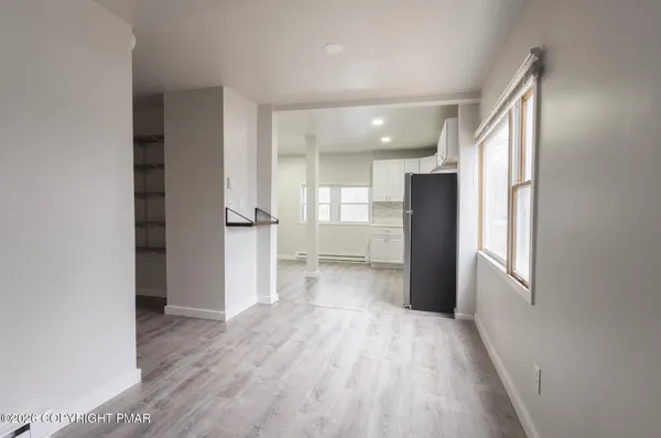 a view of a kitchen with a refrigerator and wooden floor