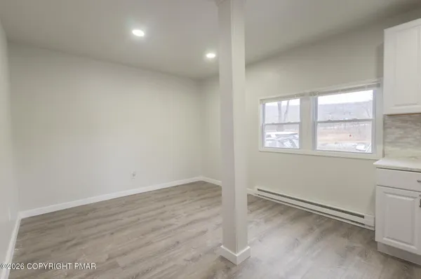 an empty room with wooden floor and windows