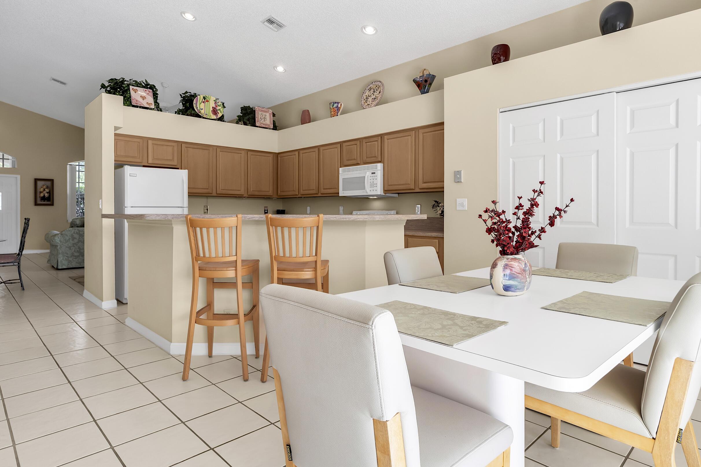 7507 Eagle Point Drive Delray Beach, FL 33446 - Photo 20 of 49 a kitchen with stainless steel appliances kitchen island granite countertop a table chairs and a refrigerator