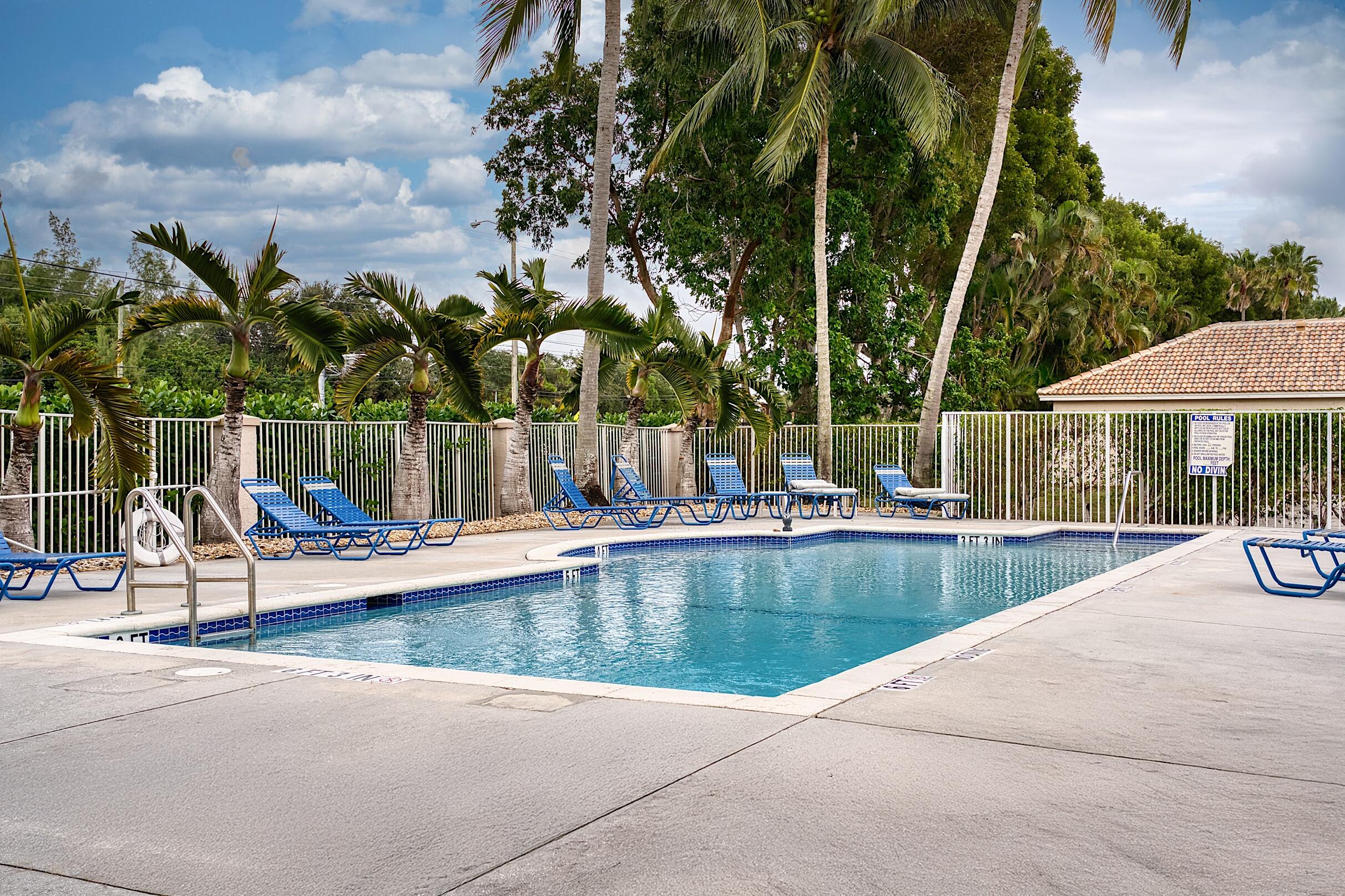 7507 Eagle Point Drive Delray Beach, FL 33446 - Photo 43 of 49 a view of a swimming pool with a table and chairs under an umbrella