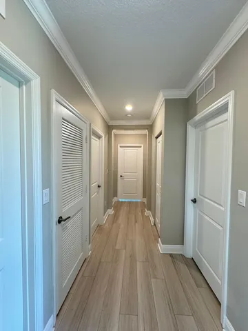 a view of a hallway with wooden floor and a bathroom