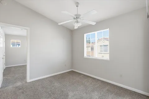 an empty room with windows and fan