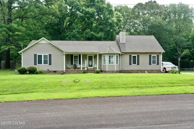 a front view of a house with a garden and trees