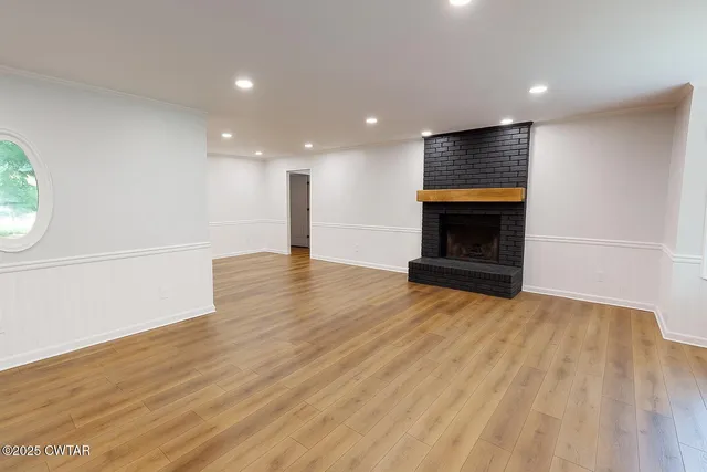 a view of empty room with wooden floor and fireplace
