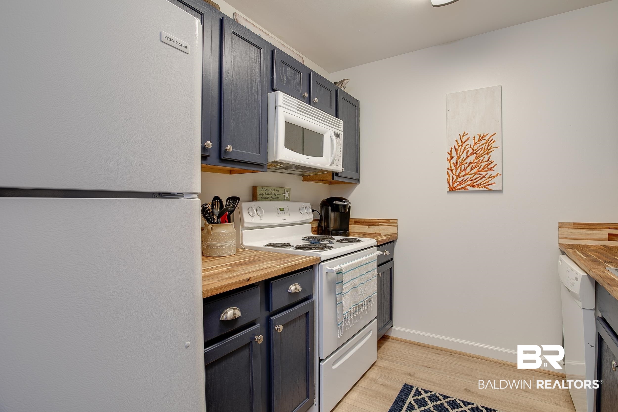 1517 Regency Road, Unit 33 Gulf Shores, AL 36542 - Photo 4 of 29 Kitchen with white appliances, baseboards, light wood finished floors, and butcher block countertops