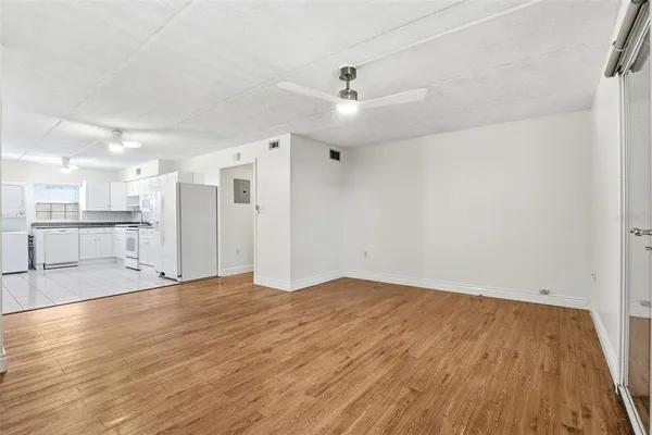 an empty room with wooden floor fan and windows
