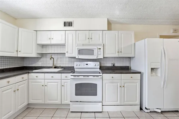 a kitchen with white cabinets and white appliances