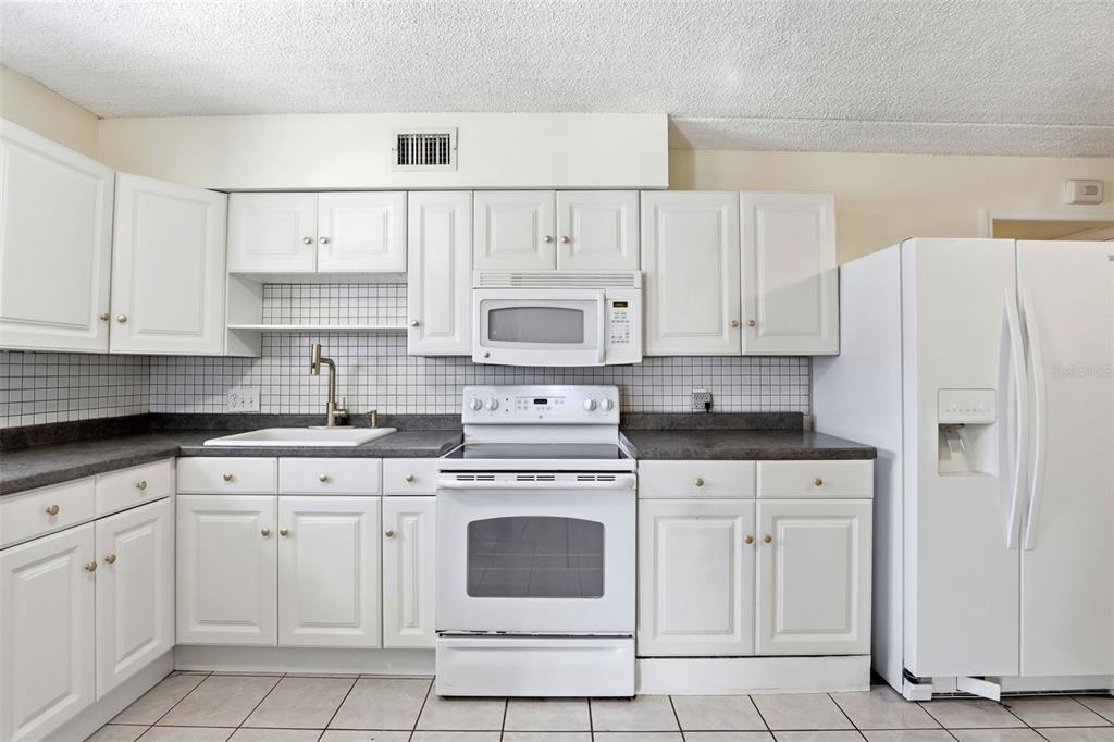 525 South Conway Road, Unit 70 Orlando, FL 32807 - Photo 3 of 28 a kitchen with white cabinets and white appliances