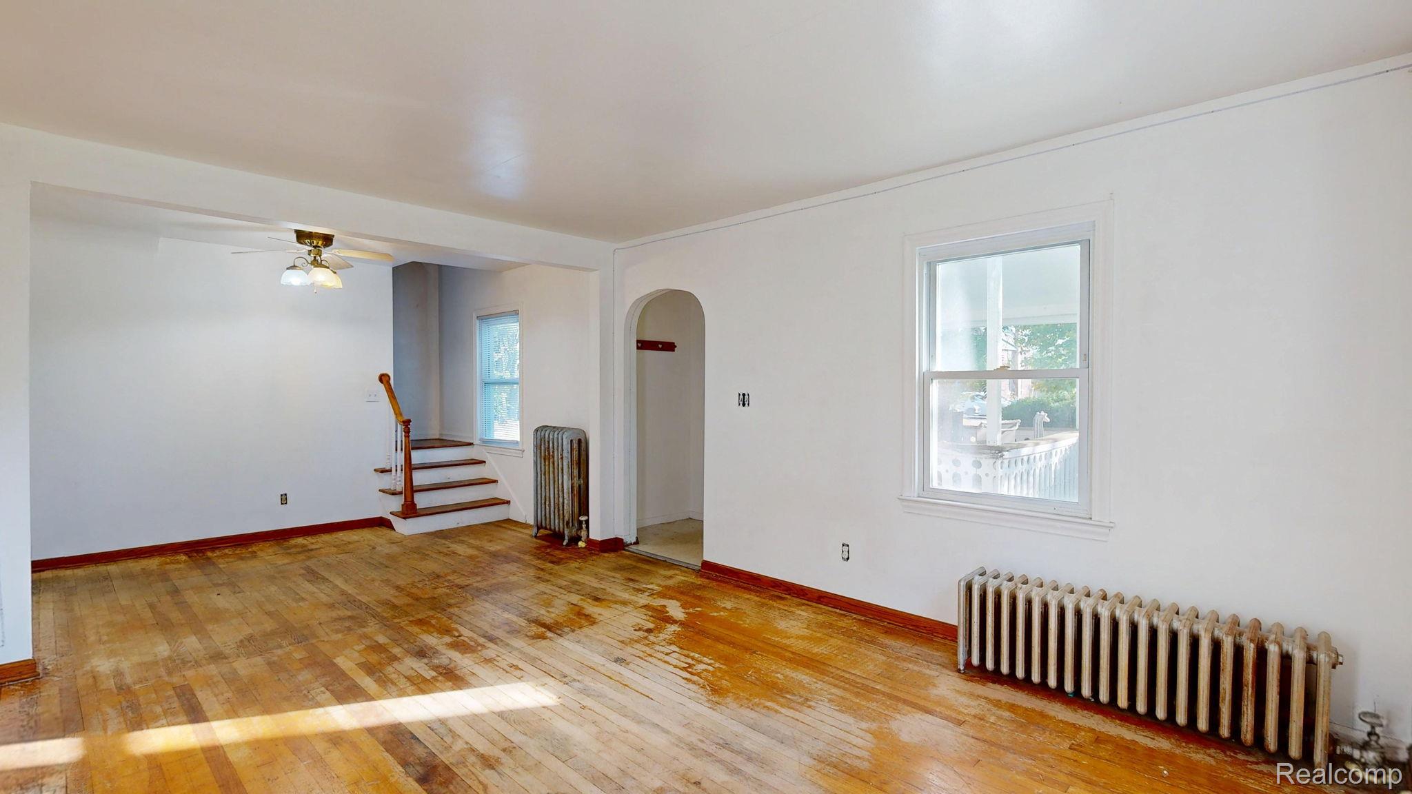 4455 North Genesee Road Flint, MI 48506 - Photo 5 of 47 Unfurnished room featuring radiator, light wood-type flooring, arched walkways, and a ceiling fan