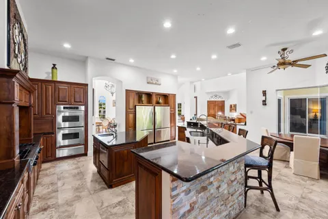 a living room with stainless steel appliances furniture a rug and a kitchen view