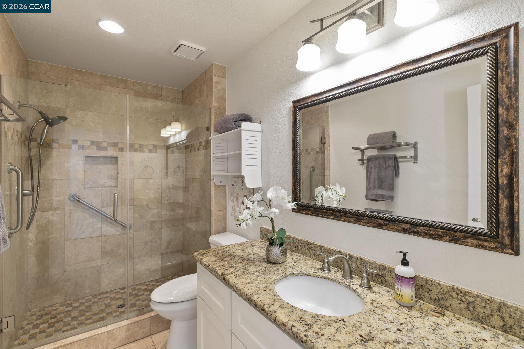 1267 Quiet Circle Concord, CA 94521 - Photo 19 of 72 a bathroom with a granite countertop sink a toilet a mirror and shower