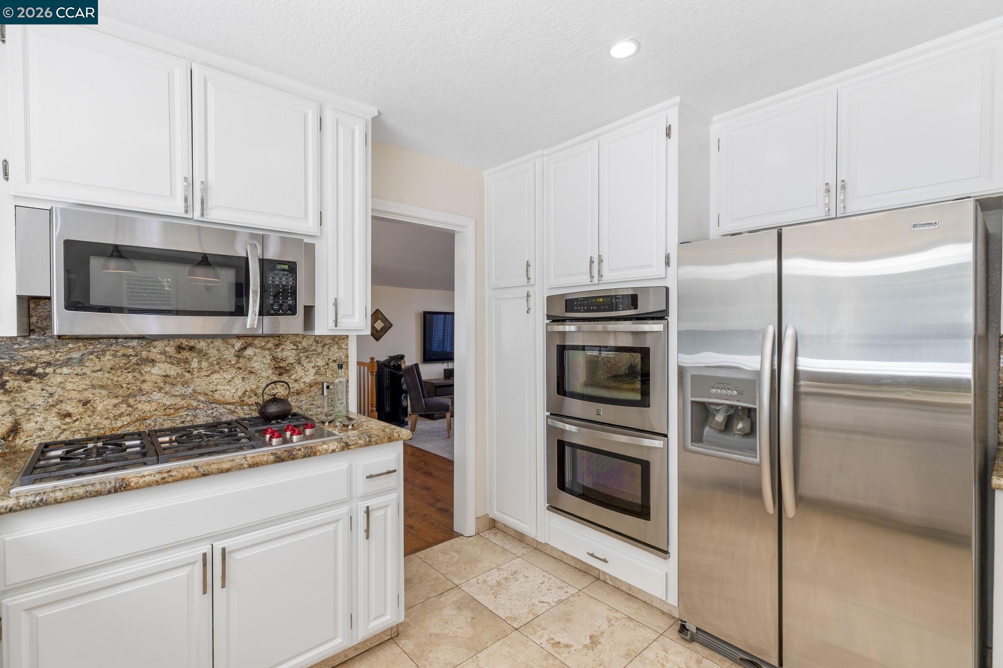 1267 Quiet Circle Concord, CA 94521 - Photo 23 of 72 a kitchen with stainless steel appliances kitchen island granite countertop a refrigerator stove and microwave